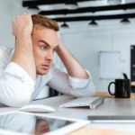Angry desperate young businessman sitting at the table